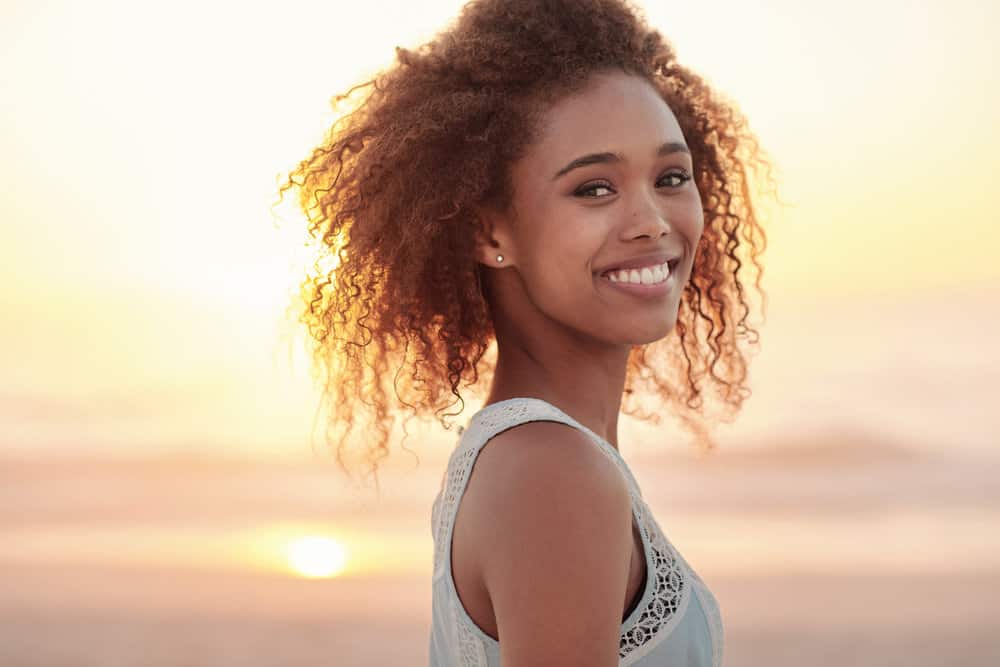 A beautiful female with a great smile wearing a wash-n-go hairstyle on her natural curls.