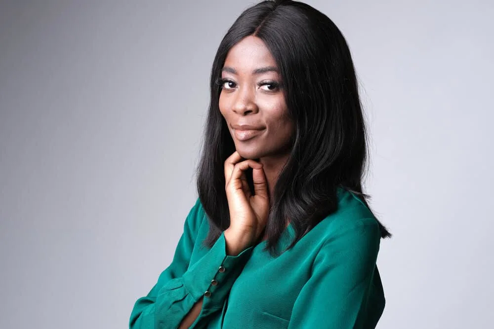 What Are Lace Wigs? How Long Do Lace Front Wigs Last on Head 7 A cheerful young African American female wearing a lace front wig with a stylish green dress.