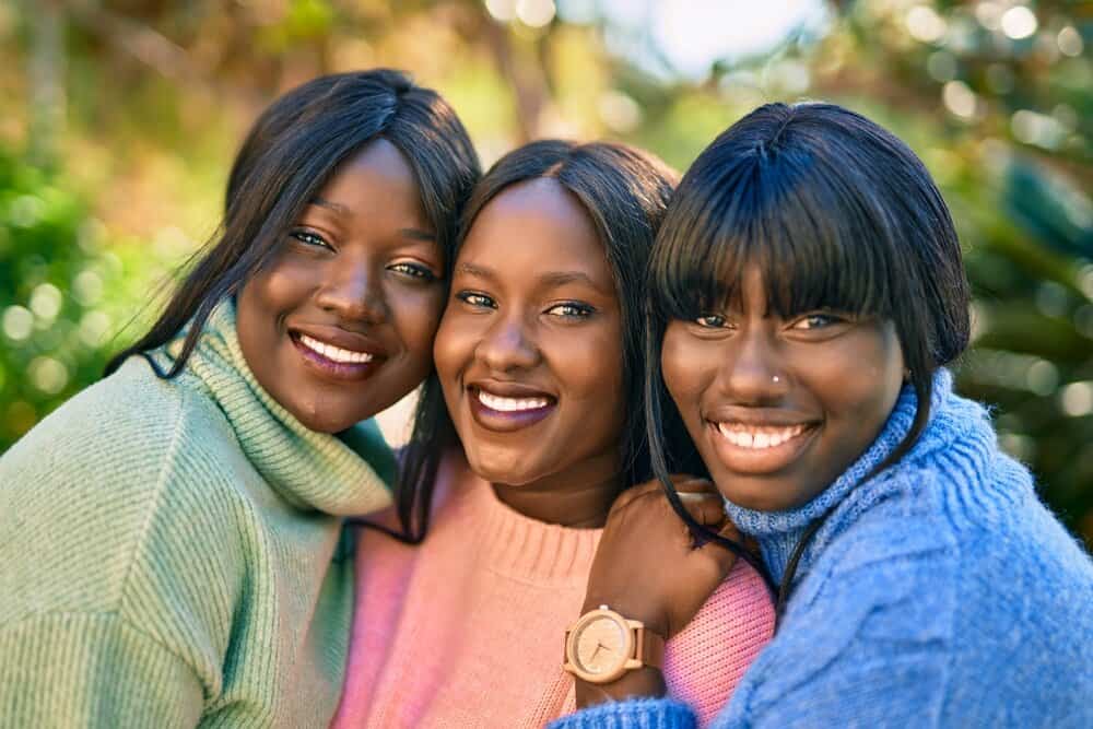 Three African American friends wearing human hair lace wigs with and without bangs covering their forehead.