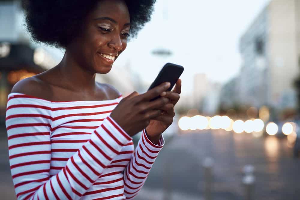 A young black female uses her mobile phone to research natural cleansing ingredients.