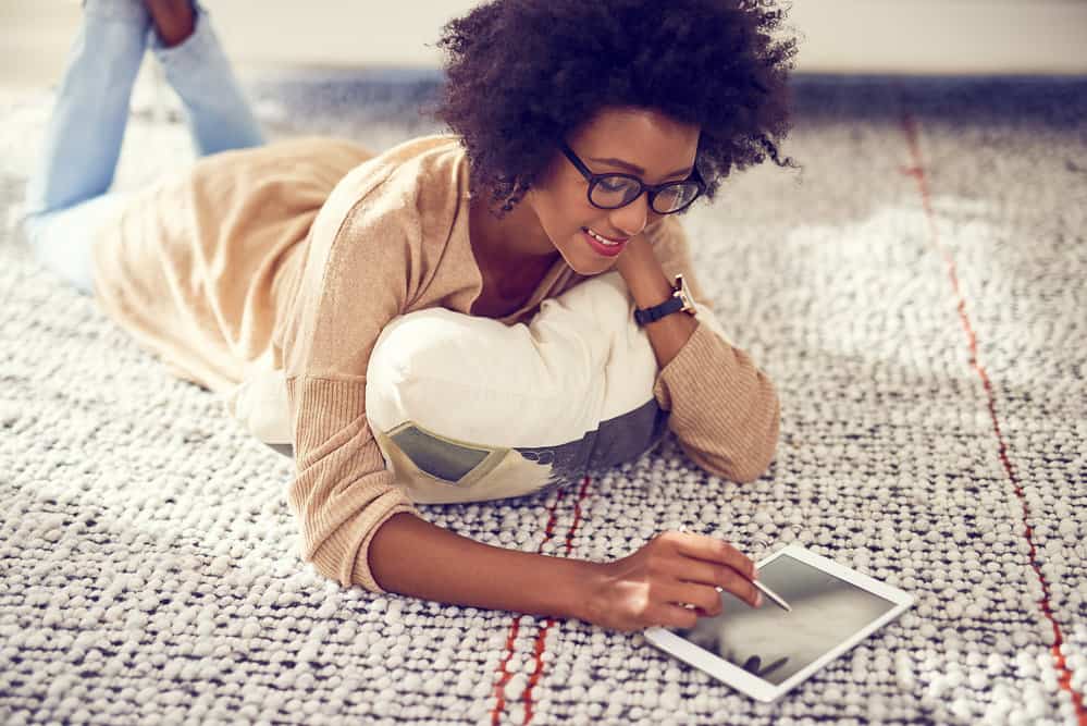 A black woman wearing a brown sweater and blue jeans with hair frizzes on her 4A curls.