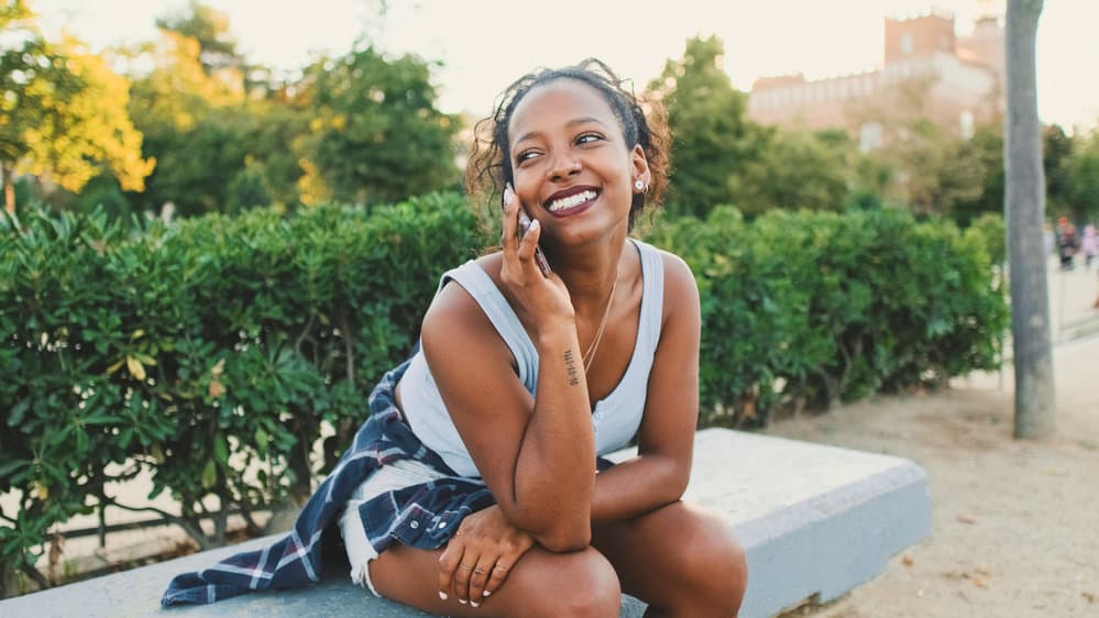 A gorgeous black lady with pretty brown skin talking to a friend about taking a gummy vitamin for hair growth.