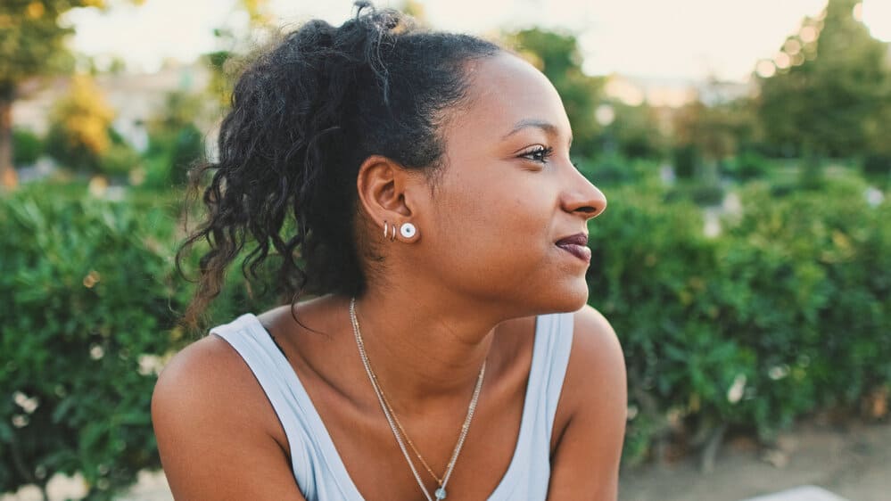 A black female with a wonderful smile uses biotin supplements and essential nutrients for new hair growth.