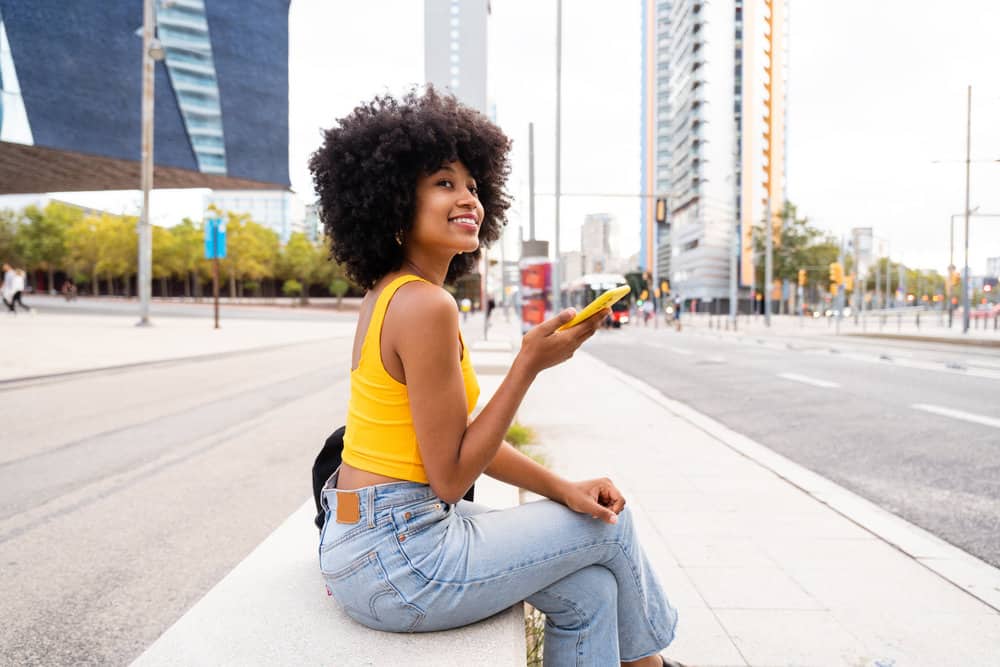 A lady with a 4B hair type has oily hair strands that have been washed with shampoo.