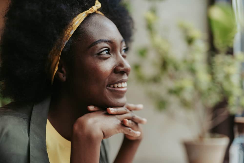 A young black woman keeps her hair healthy by following the advice of natural hair influencers.