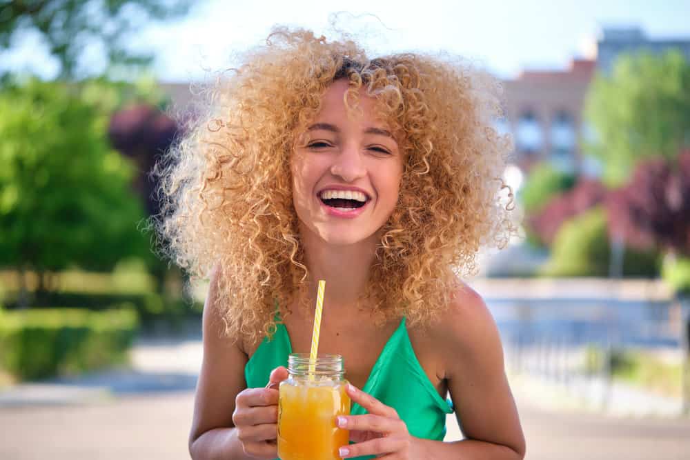 A young female is filming a video review for her stylist after using custom-mixed hair toner.