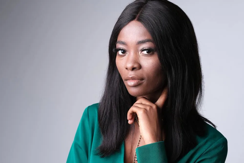 What Are Lace Wigs? How Long Do Lace Front Wigs Last on Head 1 A black woman with a chocolate skin tone is wearing a synthetic hair wig covering her own hair texture.