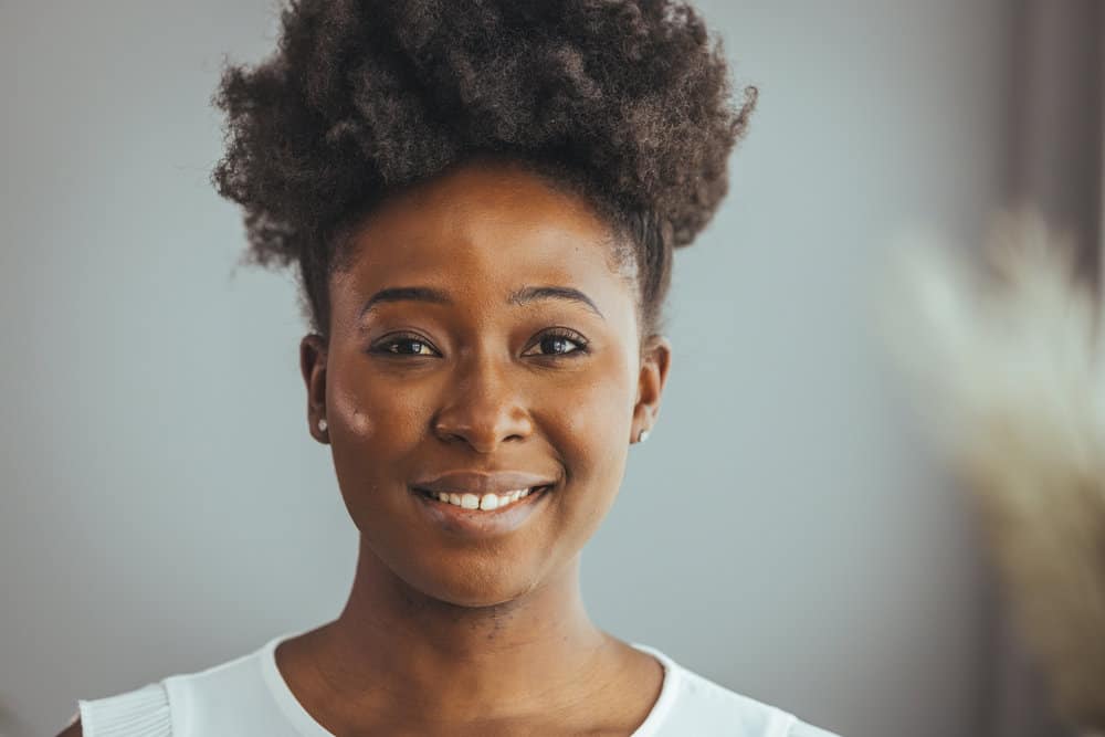 A black woman with 4C natural hair strands styled with a leave-in conditioner to retain moisture.