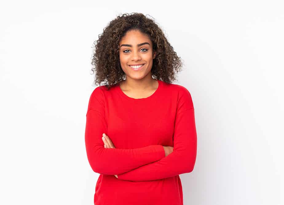 A beautiful young black woman wearing a red sweater uses different essential oils to style wash and go style.