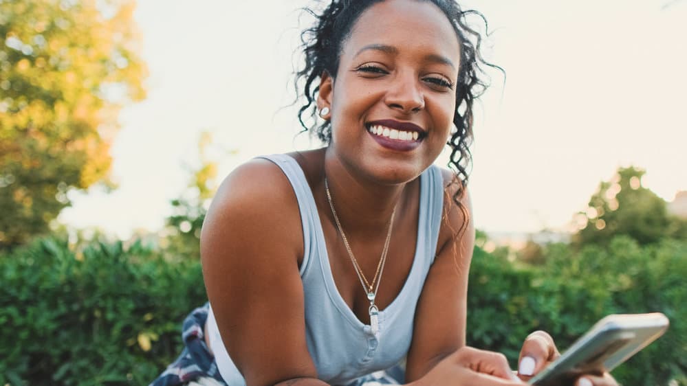 A cute black female that is talking to a friend about whether hair growth vitamins work.