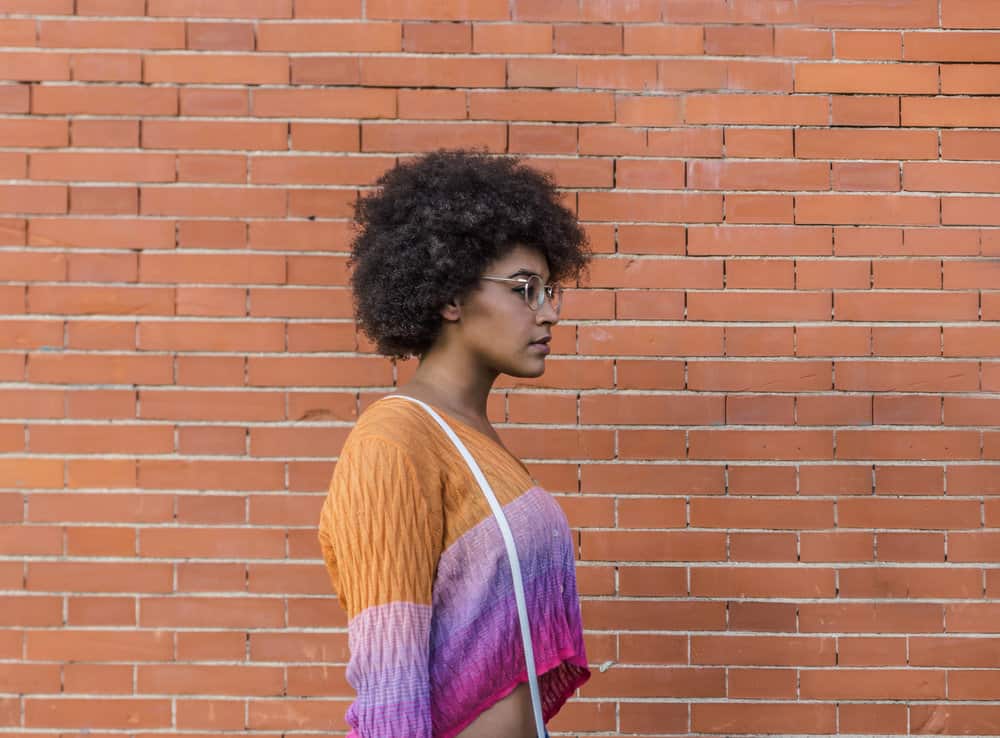 A black girl with a dark hair color and bright reddish brown undertones used henna to dye black hair.