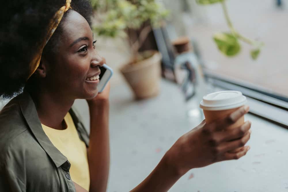 An African American female talking to a friend about wearing protective styles to encourage hair growth.