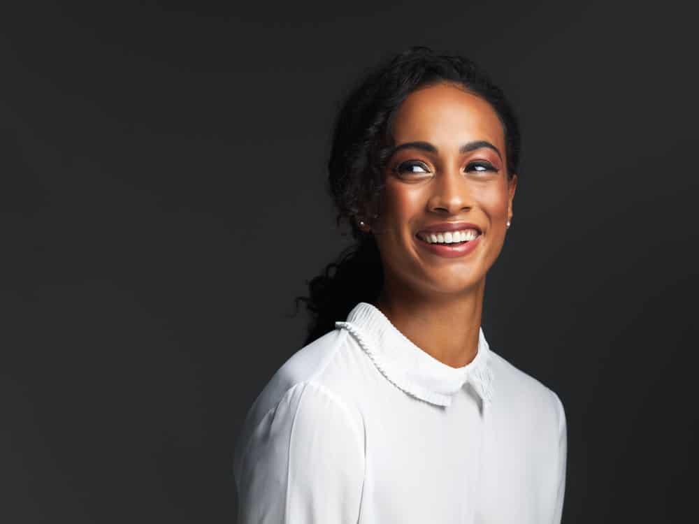 The pretty black woman showcases her thick hair with bouncy curls, achieved using a traditional curling iron that ensures minimal hair shaft damage.