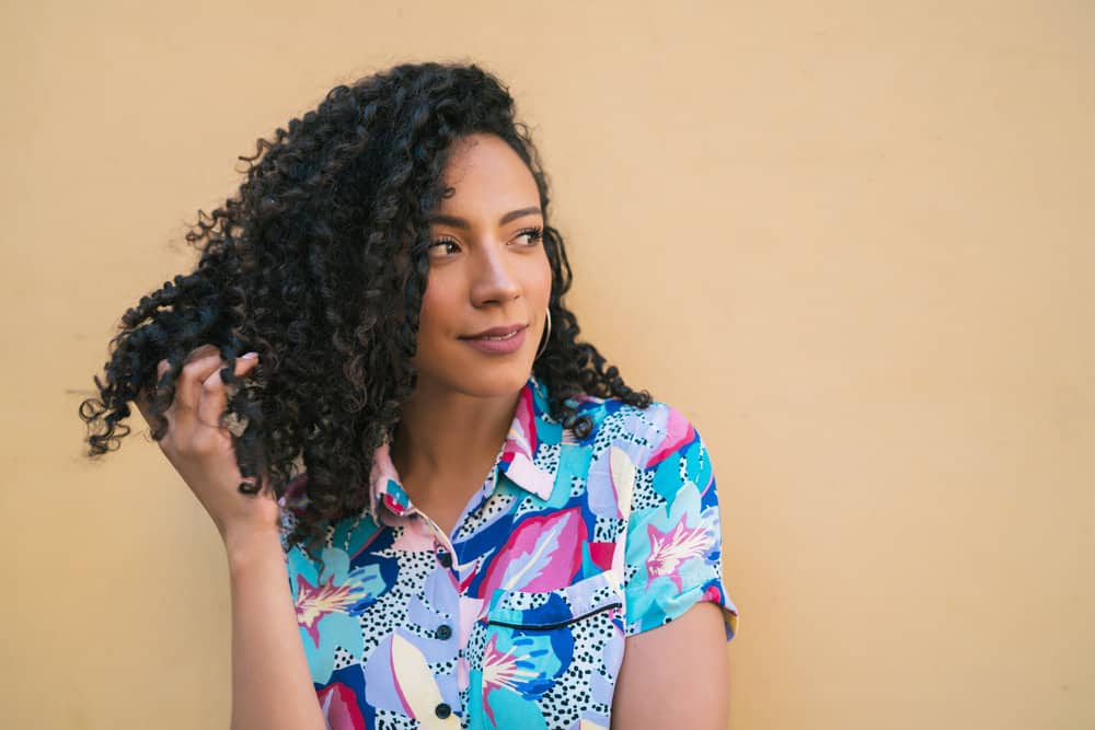 The pretty black woman effortlessly rocks beachy waves, achieved by using a curling wand and paddle brush on her naturally coarse hair strands.