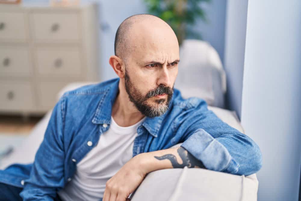 With his hair length kept short, the young man embraces his bald head, showcasing his masculine charm and embracing his unique style.