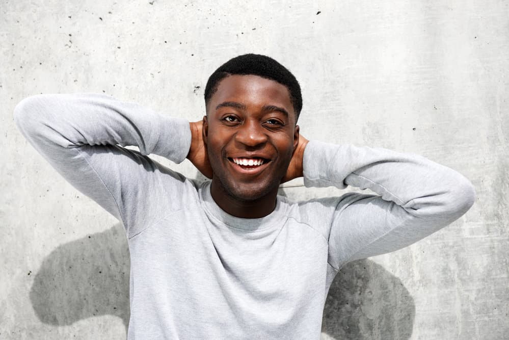 The black man's modern high fade haircut on dark hair requires little effort each morning, making it a low-maintenance hairstyle that suits his busy lifestyle.