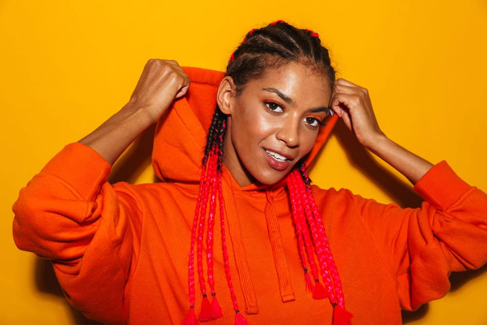 A gorgeous African American lady wearing cornrows or boxer braids with reddish hair extensions on a type 3 natural hair texture.