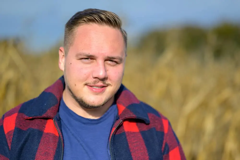 Best Haircuts for Men with Round Faces: Chubby Hairstyles for Guys 9 Sporting a classic pompadour, the young man embraces a modern and flattering haircut for round faces, accentuating his masculine features.