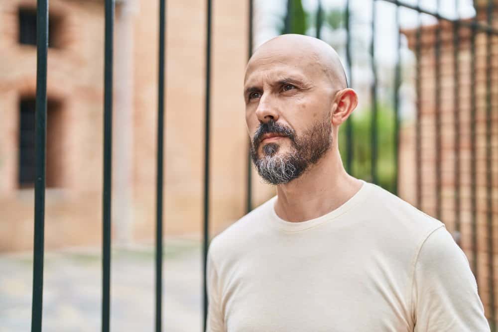 The young man embraces his thin hair by confidently sporting a shaved head, accentuating his masculine features.