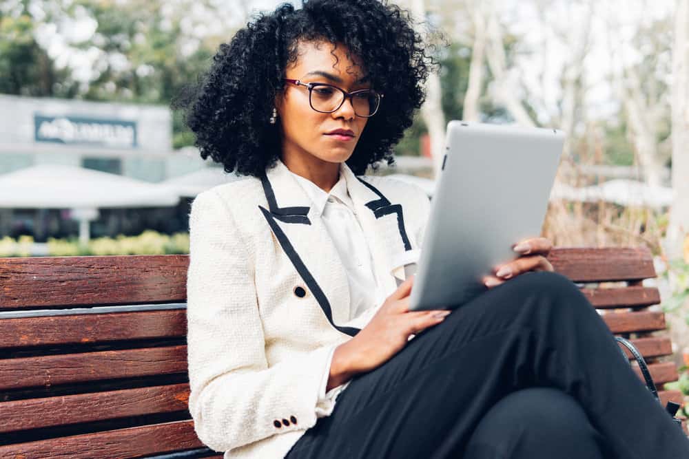 The black businesswoman's thick hair is tamed with the help of a microfiber towel and a diffuser attachment on her hair dryer, leaving her with frizz-free, bouncy curls.