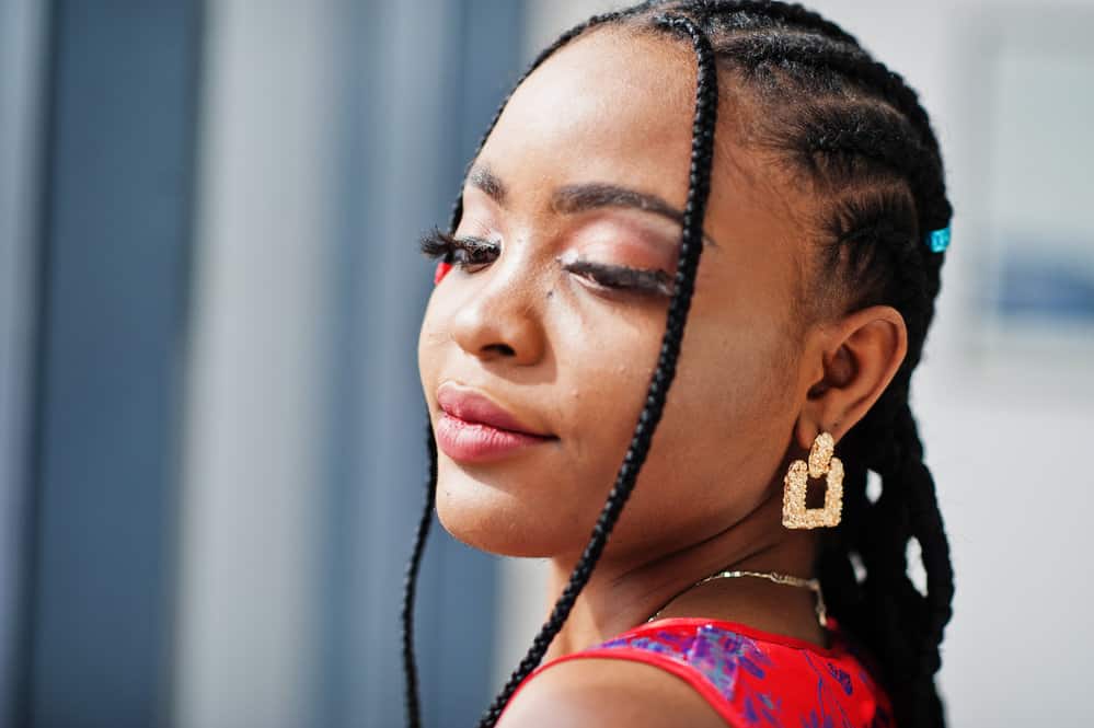 A cute black woman wearing her hair braided in a tight style with synthetic hair making her hair and scalp feel tender from the tight cornrows.