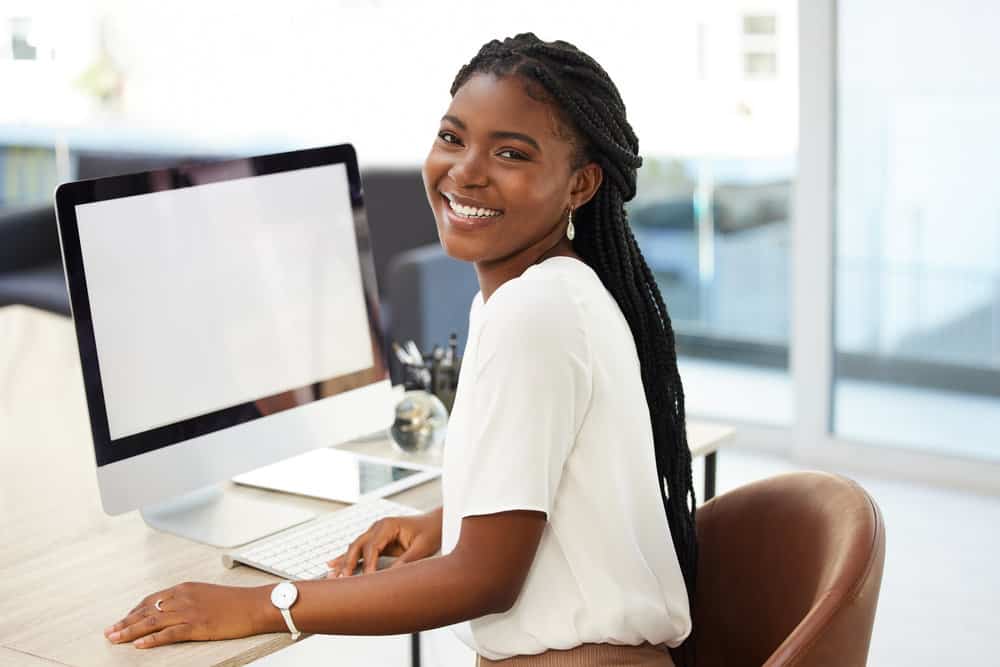 A beautiful black lady wearing traditional box braids using a knotless braid installation method and human extension hair creates a classic protective style.