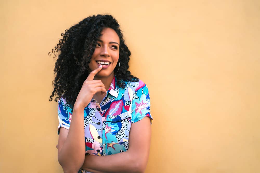 With a wide-tooth comb, she gently detangles her wet hair, ensuring that her natural curls are primed for the beach wave style.