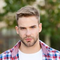 A stylish white guy with an oval face shape and thin hair is wearing a big forehead haircut with his receding hairline.