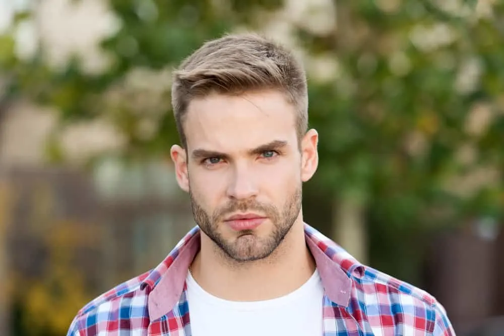 Hairstyles for Men with Big Foreheads: Step-by-Step Tutorials 1 A stylish white guy with an oval face shape and thin hair is wearing a big forehead haircut with his receding hairline.