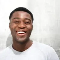 A black man wearing a modern high fade haircut on dark hair that requires very little effort each morning with hair on top of the head of this low maintenance hairstyle.