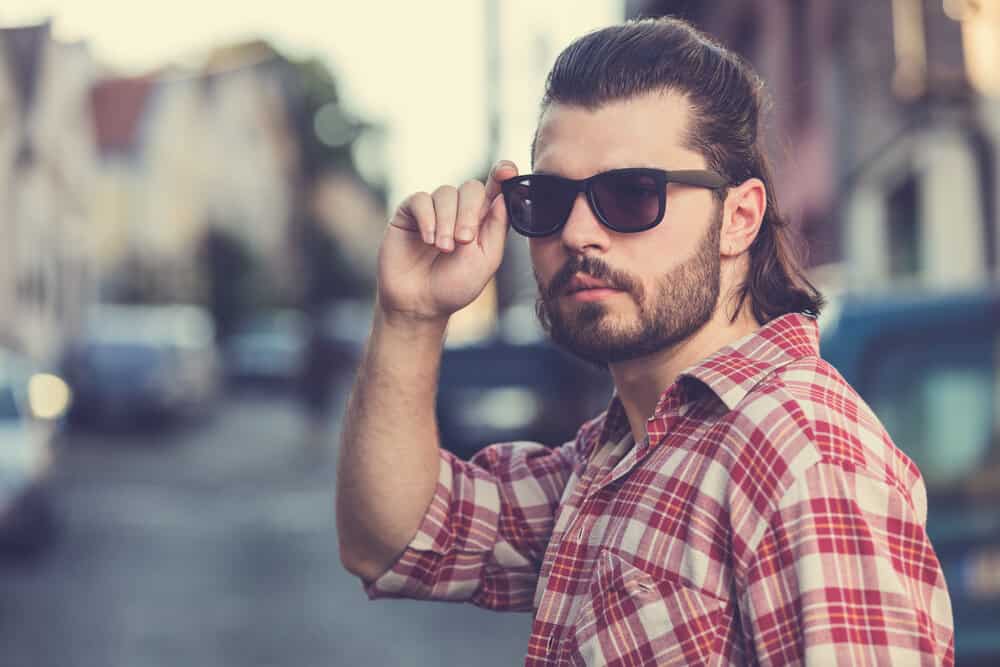 His naturally curly hair is tamed into a stylish mullet, with the flowing locks in the back adding an element of coolness.