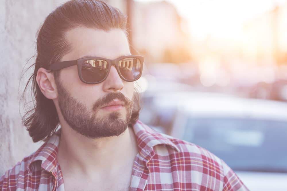 The guy confidently rocks his thick, straight hair in a short Mexican mullet haircut, exuding an edgy and fashionable vibe.