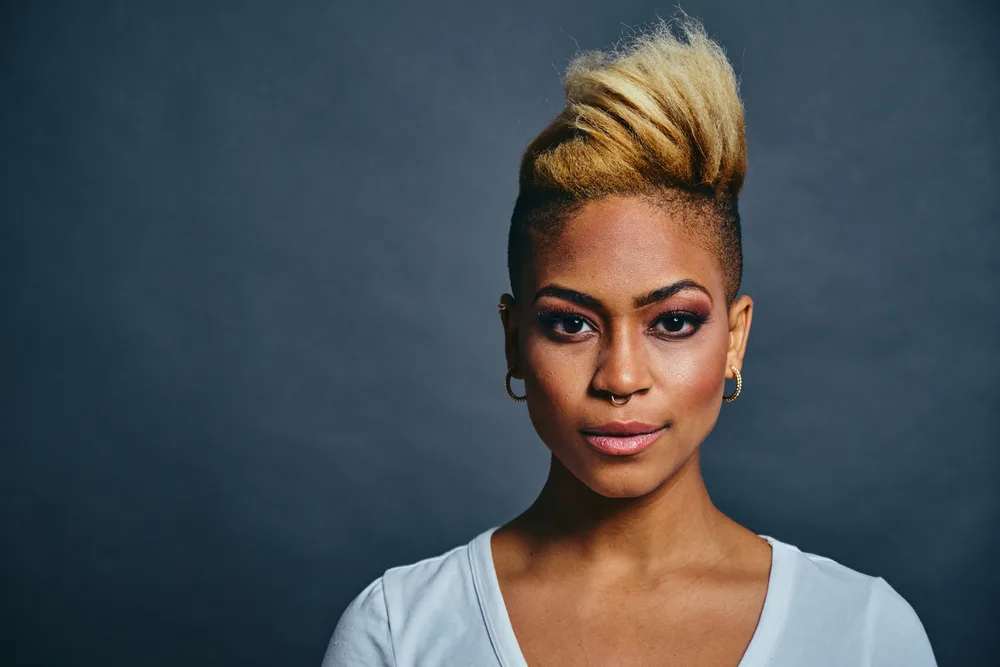 An African American female showcases her gorgeous dark hair tone transformed to blonde with box dye and 20-volume developer, creating a beautiful and bold hair color.