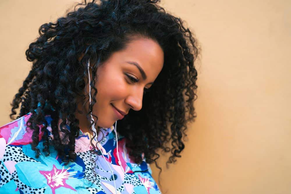 A beautiful black lady with fine hair wearing beachy waves created with a curling wand and paddle brush on her naturally coarse hair strands.