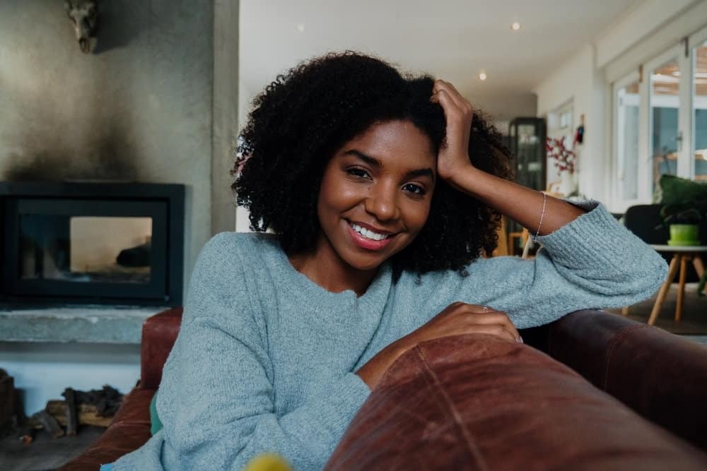 A cute dark skin lady with voluminous curly hair and a 4A natural curl pattern wearing a Deva cut on her natural curly hair.