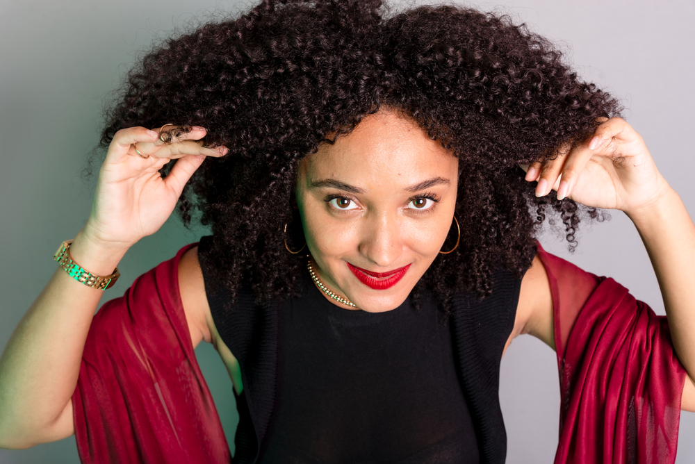 A beautiful young black girl with dark brown wavy hair and voluminous curls styled with a low-heat hair dryer and a few drops of hair oil, creating minimal frizz and defined curls.