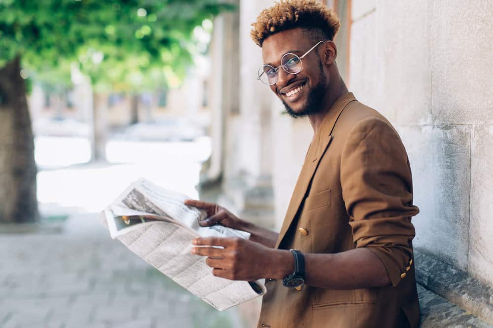 A young black man with bleached hair tips on naturally dark brown hair strands with a type 4 hair texture.