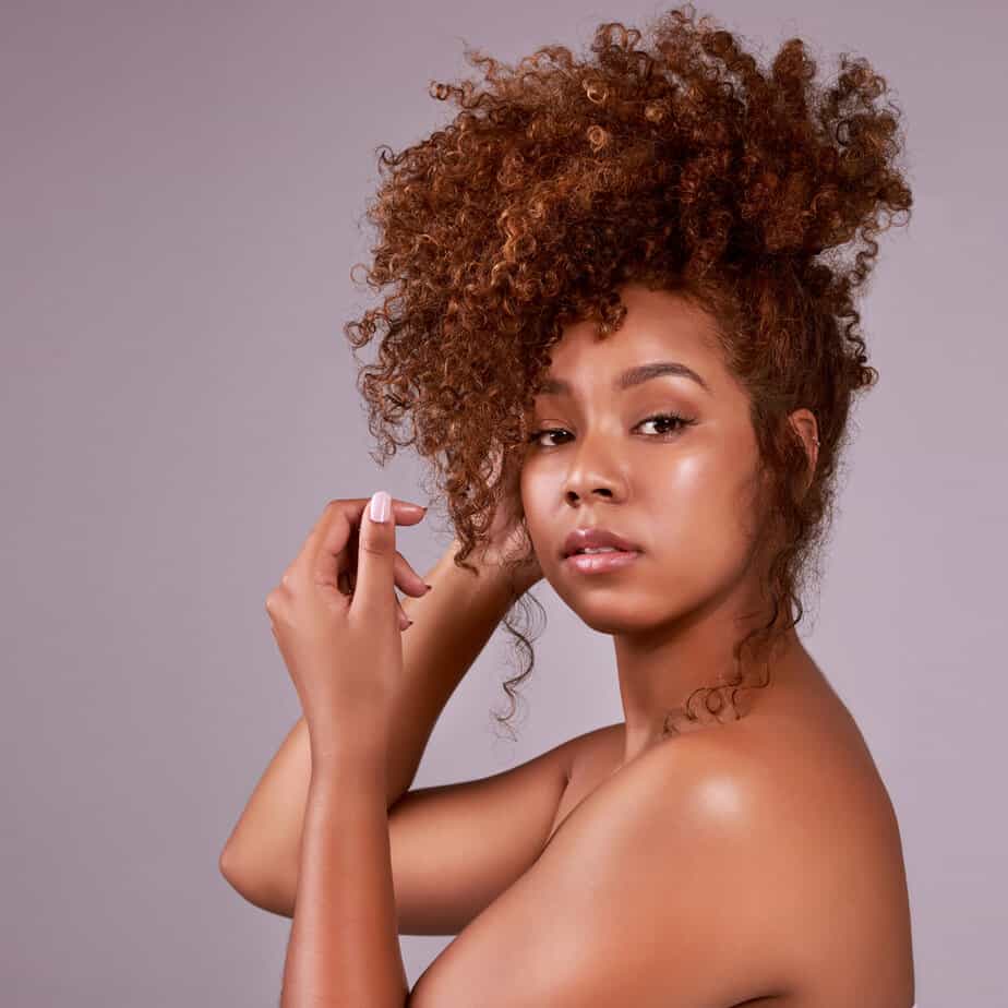 A young African American female with towel-dried hair with little curls hanging down by her face.