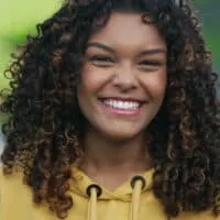 A young Brazilian girl with color-treated hair has a slightly darker hair color than most ladies with brown hair and curls styled with natural oils and a wide-tooth comb.