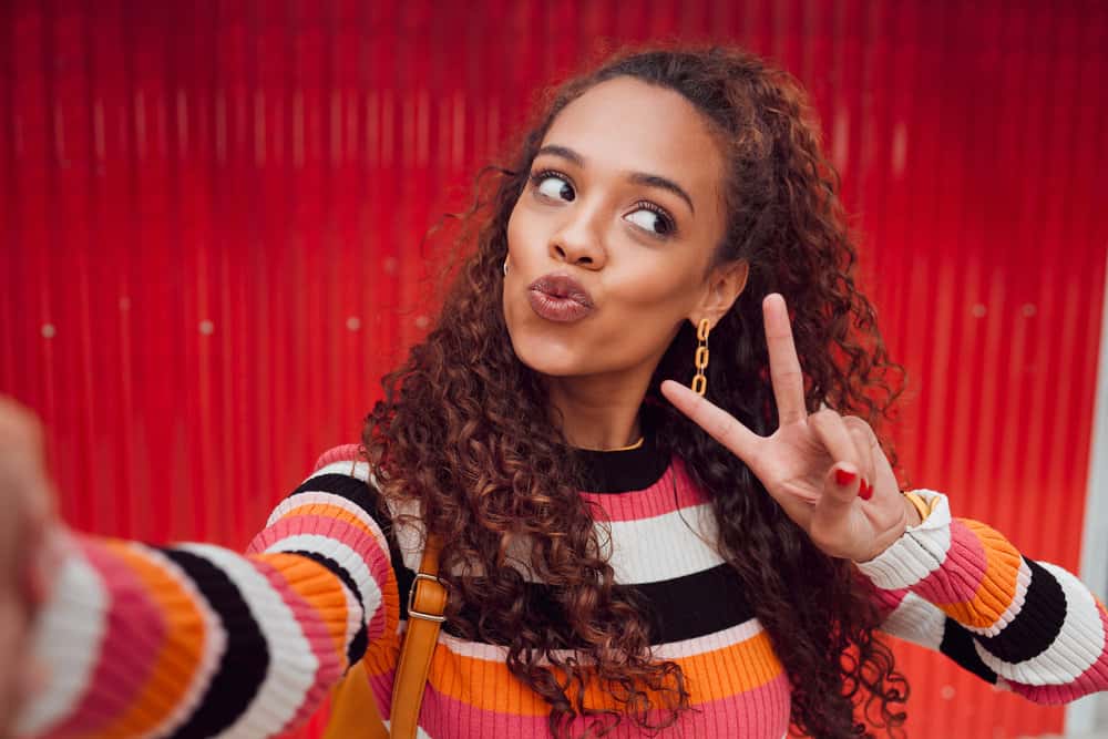 A fashionable young black girl wearing her naturally straight hair curly after using sea salt spray and natural oils on her soaking wet hair strands to create defined curls.