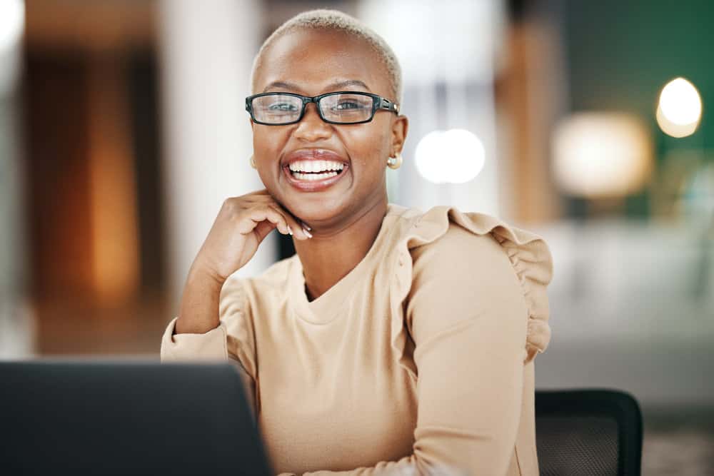 A cute African American female with dark brown skin wearing colored hair dyed with a blonde semi-permanent hair color covering her black natural shade.