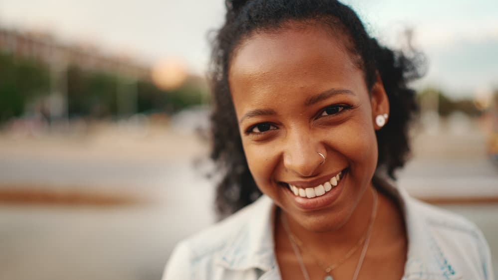 A young black female with a wavy natural curl pattern used the Curly Girl Method to make her wavy hair curlier and keep her defined curls hydrated.