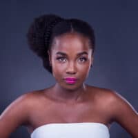 A stunning black girl with fine hair maintains moisture with natural oils, like coconut oil and shea butter, for healthy hair growth.