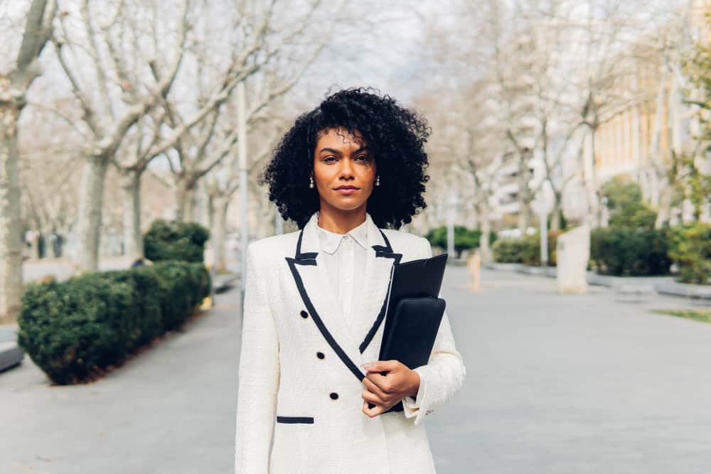 A black businesswoman with naturally curly hair has a type 3 natural curl pattern cleaned with a curly hair shampoo and styled with curl cream.