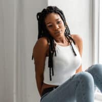 A fashionable black female with crochet faux locs and styled baby hairs made with Kanekalon hair that looks like natural locs.