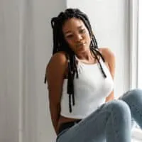 A fashionable black female with crochet faux locs and styled baby hairs made with Kanekalon hair that looks like natural locs.