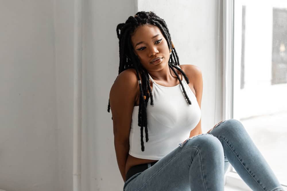 A fashionable black female with crochet faux locs and styled baby hairs made with Kanekalon hair that looks like natural locs.