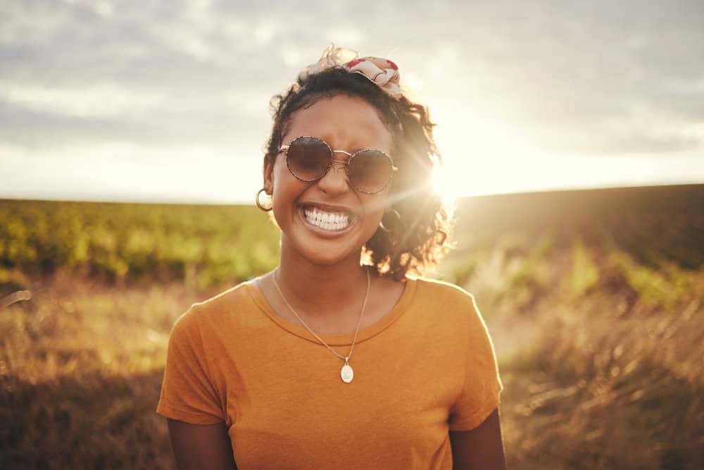 A black woman with beautiful skin that uses organic skin and haircare products with fatty alcohols and emollient properties.