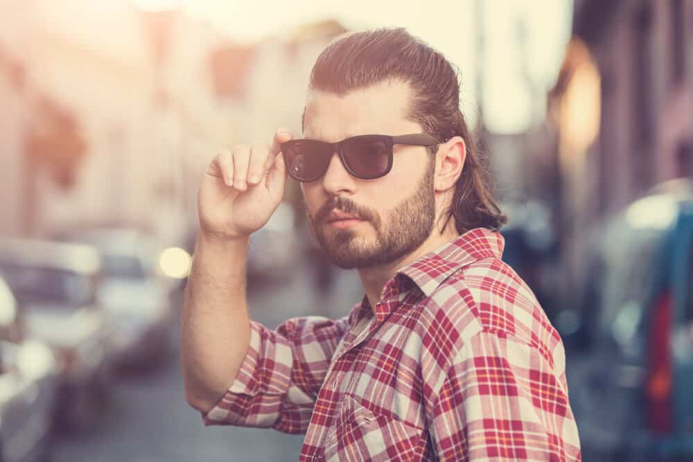 With the right hair product, he enhances the natural curls of his mullet, adding extra volume and definition to his unique hairstyle with sideburns.