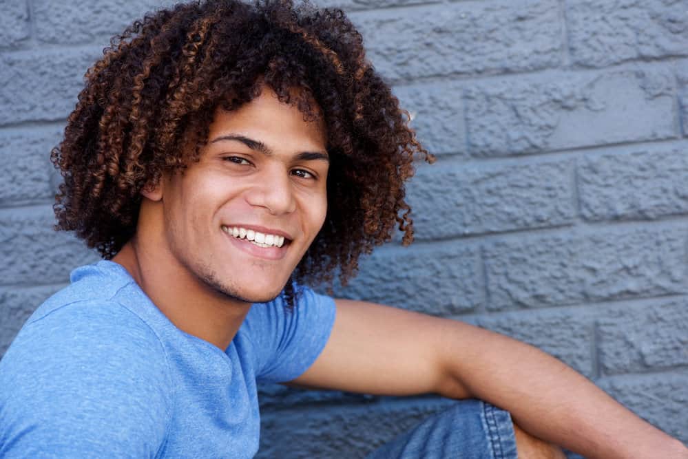 This young man shows off his thick tresses styled in a laid-back men's long hairstyle, showcasing an on-trend ombre effect.